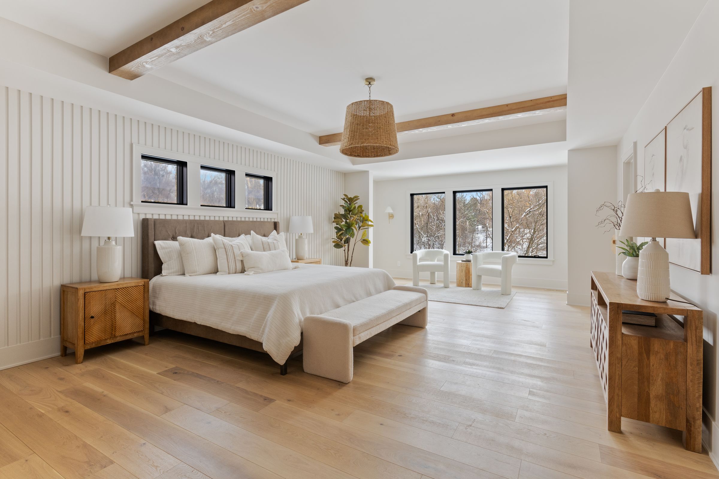 Primary bedroom with a vertical slat accent wall, clerestory windows, stained ceiling beams, and a woven pendant