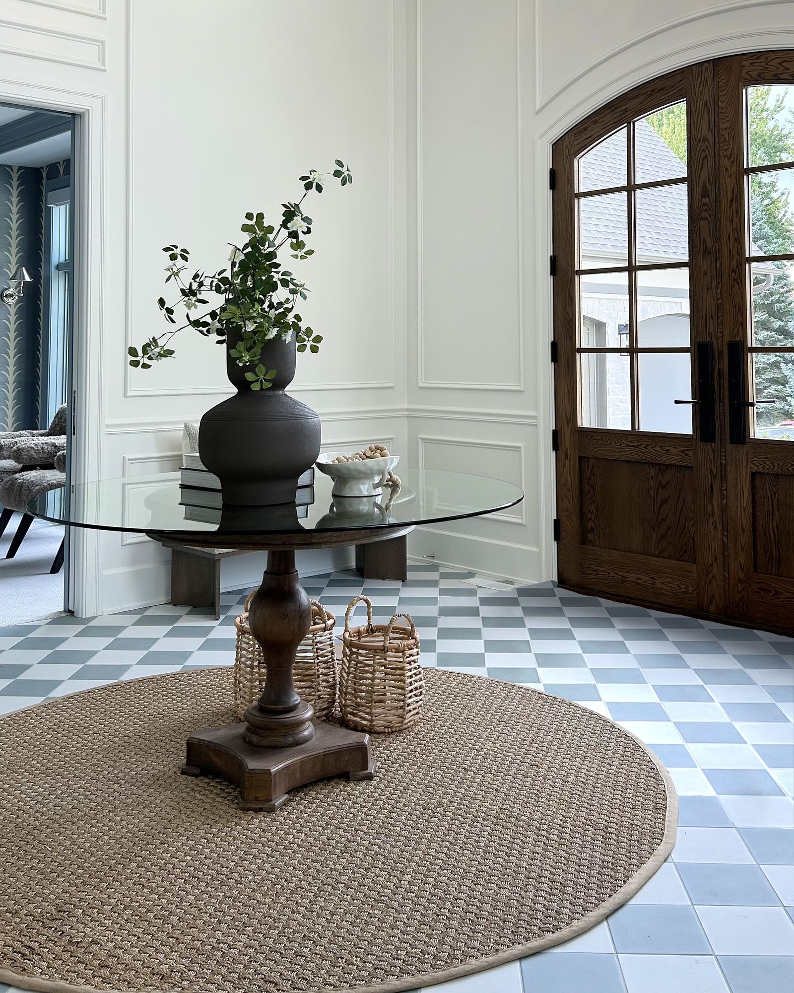South Lane foyer with arched front doors, picture-frame wall moulding, and a checkerboard tile floor