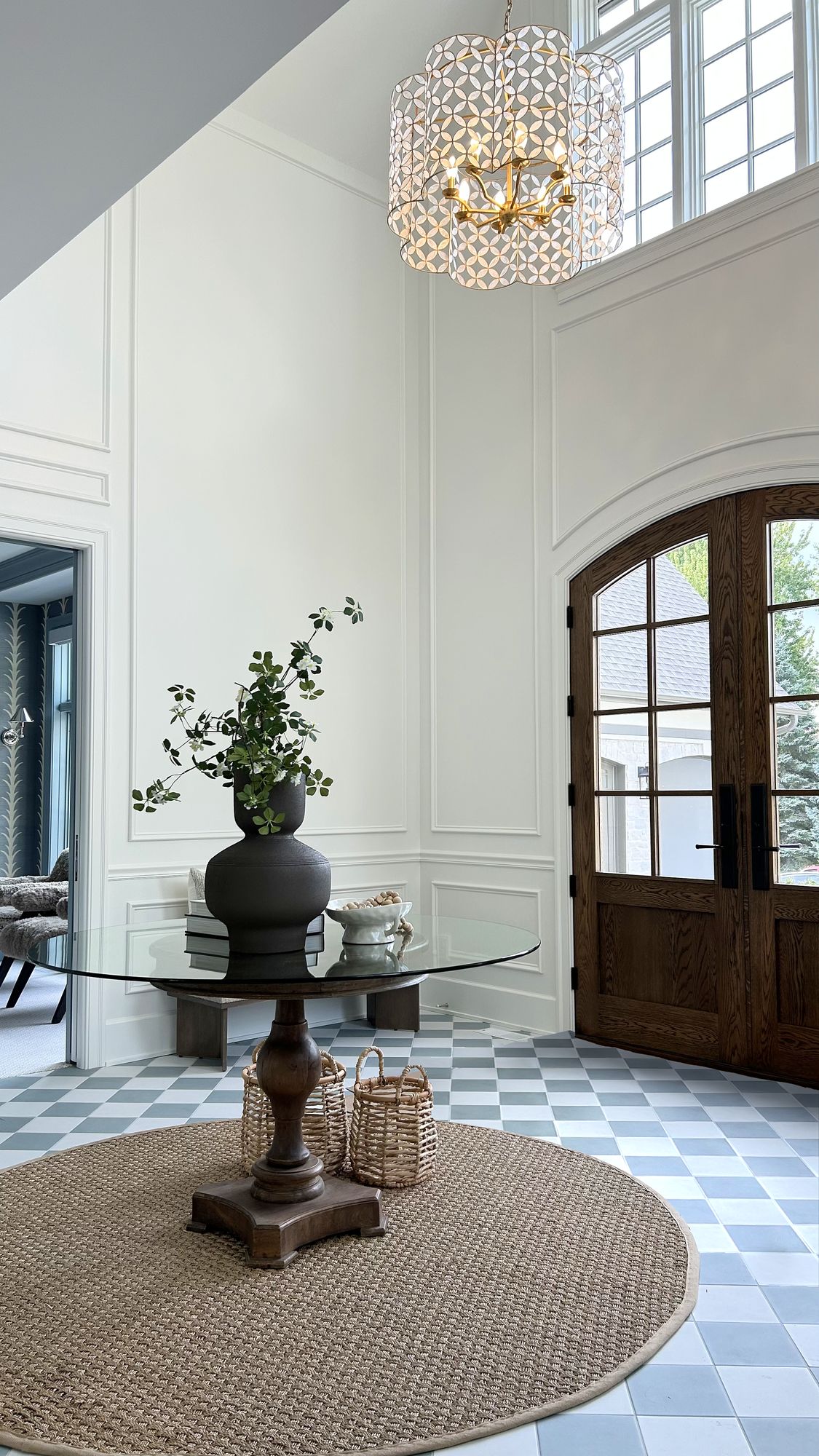Grand foyer with picture-frame wall moulding, a scalloped pendant, and arched wood front doors