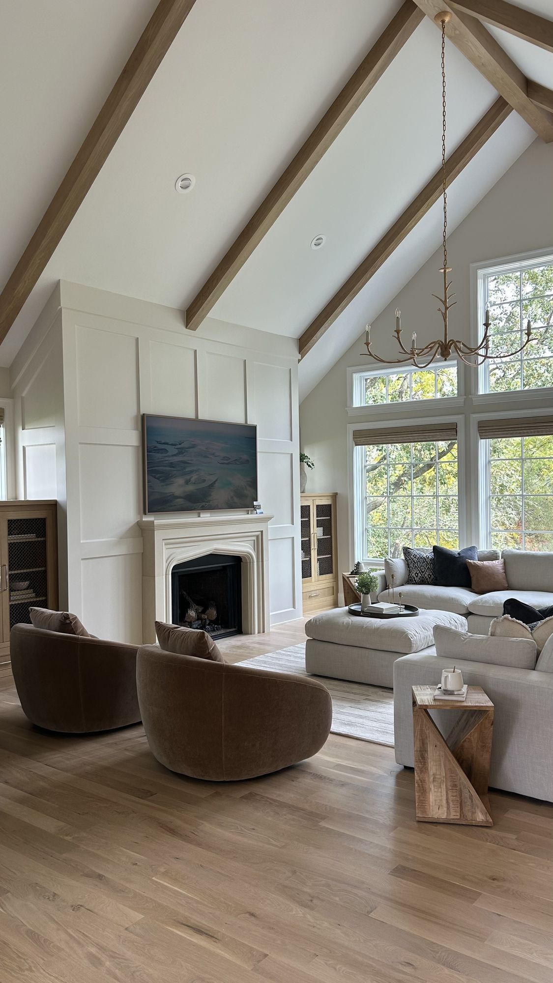Great room with a vaulted beamed ceiling and a paneled fireplace wall with a Tudor-arched stone mantel