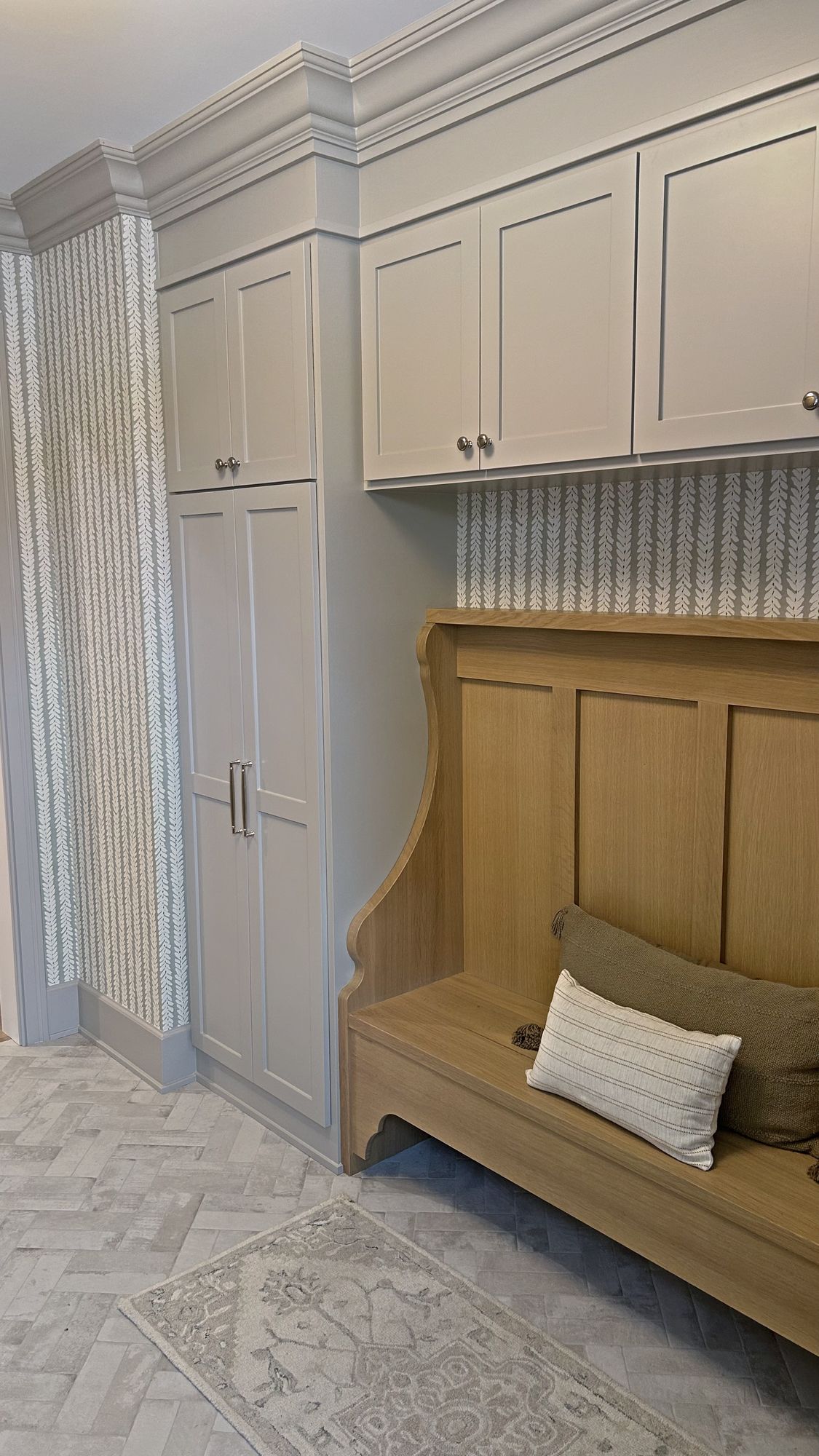 Mudroom with floor-to-ceiling cabinetry, leaf-pattern wallpaper, a white oak built-in bench, and a herringbone floor